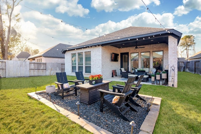 back of property with brick siding, fence, a ceiling fan, a yard, and an outdoor living space with a fire pit