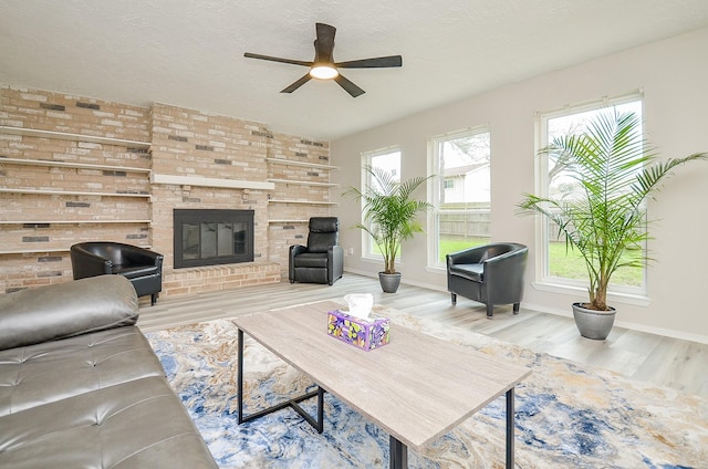 living room with ceiling fan, a fireplace, a textured ceiling, and wood finished floors