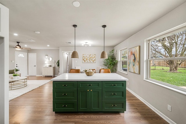 kitchen featuring dark wood-style floors, a center island, light countertops, and green cabinets