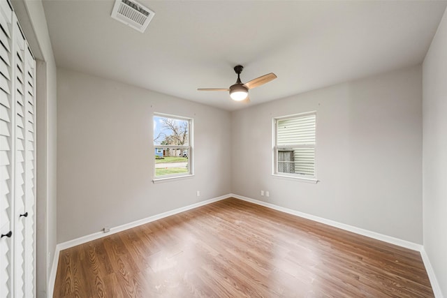 empty room with a ceiling fan, visible vents, baseboards, and wood finished floors