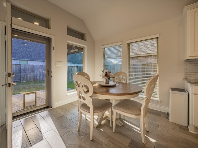 dining space featuring wood finish floors, baseboards, and lofted ceiling