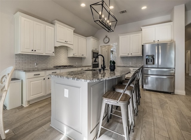 kitchen featuring visible vents, white cabinetry, stainless steel appliances, and a sink