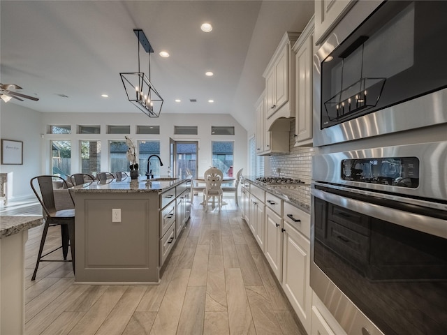 kitchen featuring a sink, a kitchen breakfast bar, stainless steel appliances, decorative backsplash, and a healthy amount of sunlight