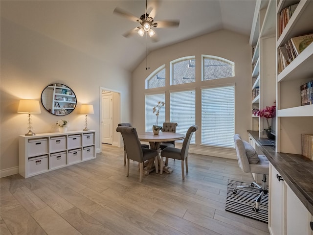 dining area featuring high vaulted ceiling, baseboards, light wood-style floors, and a ceiling fan