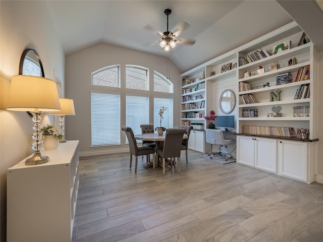 dining room featuring light wood finished floors, lofted ceiling, ceiling fan, and built in study area