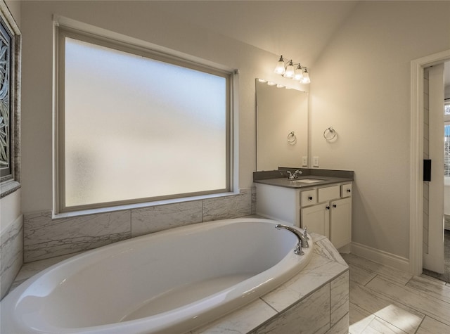 bathroom with a wealth of natural light, baseboards, a bath, and vanity