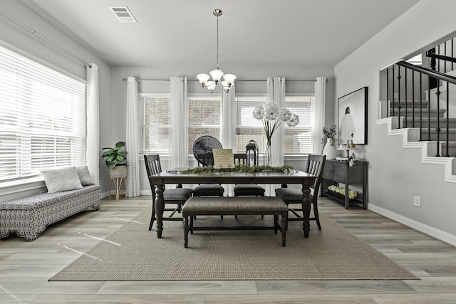 dining room featuring a healthy amount of sunlight, stairway, visible vents, and a chandelier