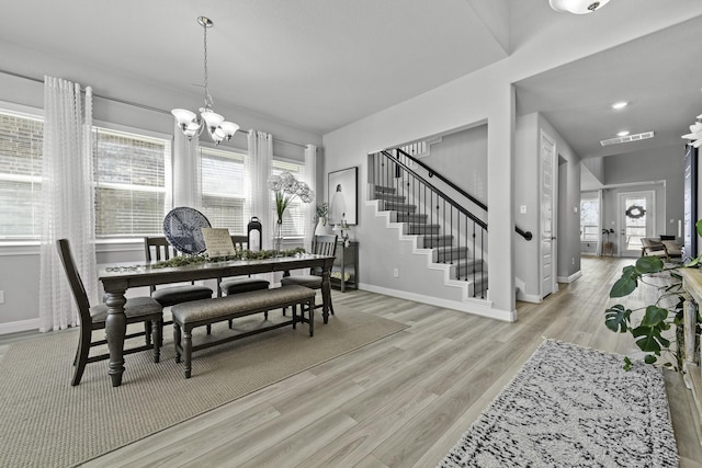 dining space with a notable chandelier, visible vents, stairway, light wood-style floors, and baseboards