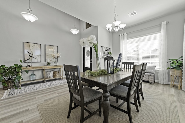 dining room with baseboards, visible vents, a notable chandelier, and light wood finished floors