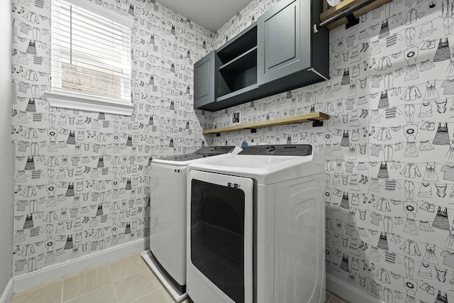 washroom with light tile patterned floors, washing machine and dryer, baseboards, cabinet space, and wallpapered walls