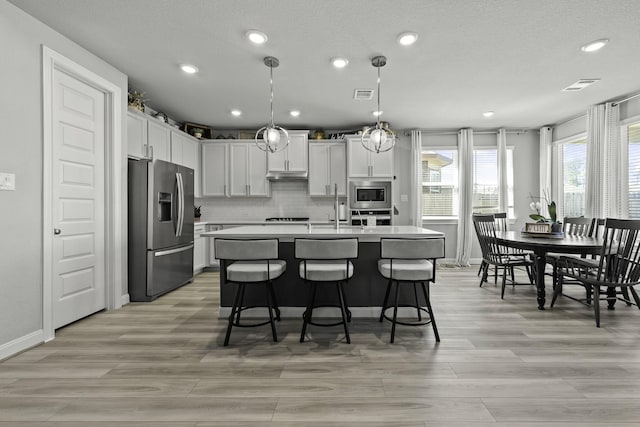 kitchen featuring hanging light fixtures, appliances with stainless steel finishes, light countertops, and white cabinets