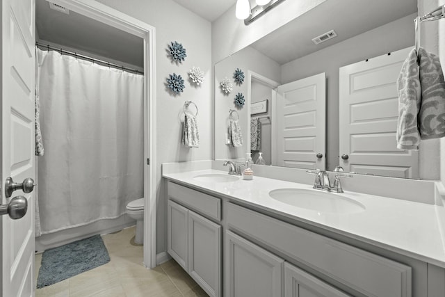 full bathroom with toilet, double vanity, a sink, and visible vents