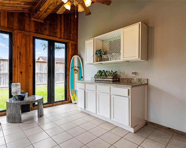 kitchen featuring light tile patterned floors, wooden walls, lofted ceiling with beams, light stone countertops, and open shelves