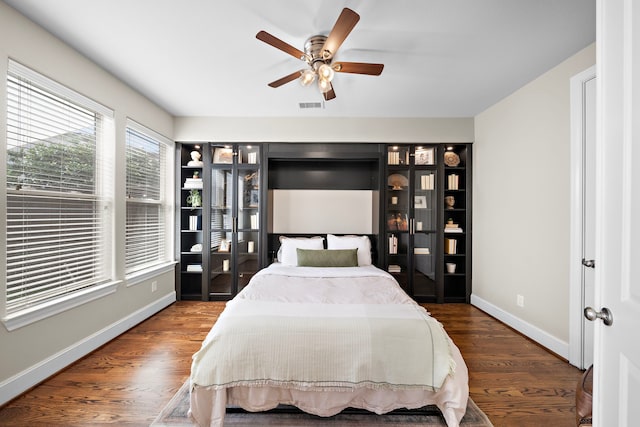 bedroom with a ceiling fan, baseboards, visible vents, and wood finished floors