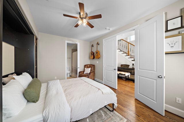 bedroom with a ceiling fan, connected bathroom, baseboards, and wood finished floors