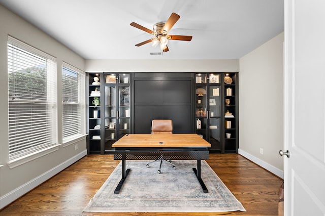 office with baseboards, dark wood finished floors, visible vents, and a ceiling fan