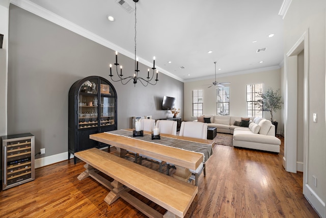 dining area with ornamental molding, wine cooler, wood finished floors, and visible vents