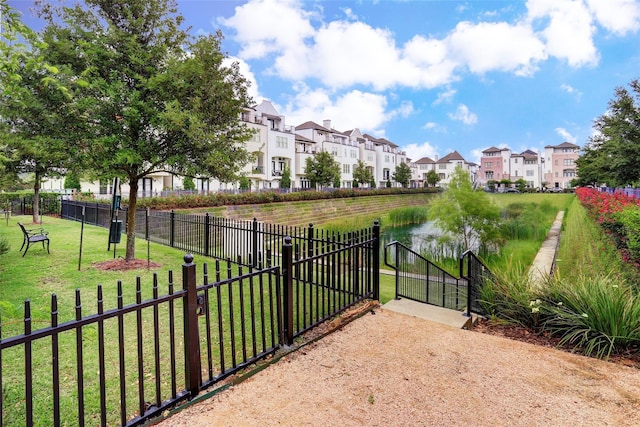 view of gate featuring a residential view, fence, and a lawn