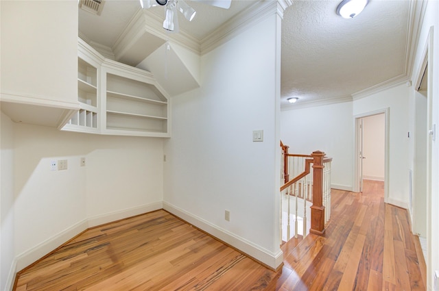 interior space featuring a textured ceiling, light wood-style flooring, a ceiling fan, visible vents, and baseboards