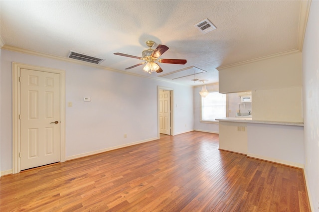 spare room featuring attic access, visible vents, ornamental molding, and wood finished floors