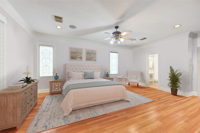 bedroom with light wood finished floors, visible vents, and crown molding