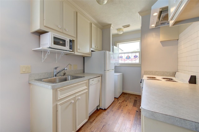 kitchen with light wood-style floors, white appliances, light countertops, and a sink