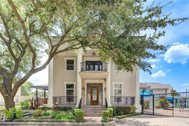 view of front facade with a porch, fence, a balcony, and stucco siding