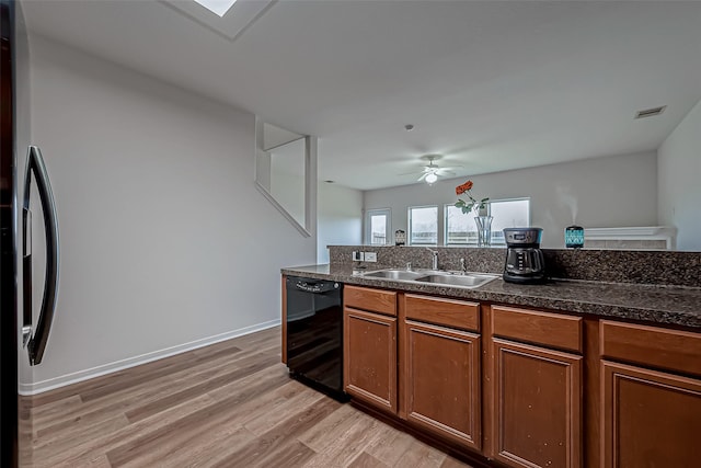 kitchen with dishwasher, dark countertops, brown cabinets, light wood-style floors, and a sink