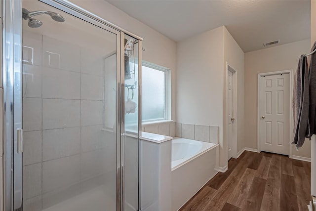 full bath with a stall shower, baseboards, visible vents, wood finished floors, and a garden tub