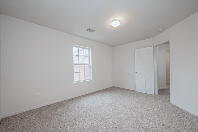 empty room with baseboards, visible vents, and light colored carpet