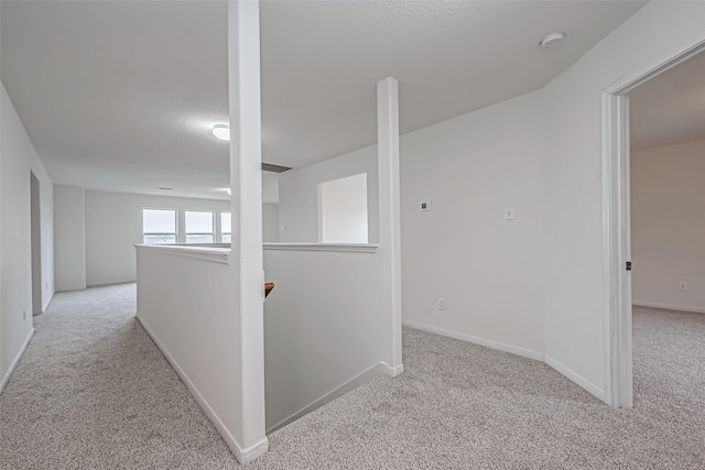 hallway with carpet flooring, an upstairs landing, and baseboards