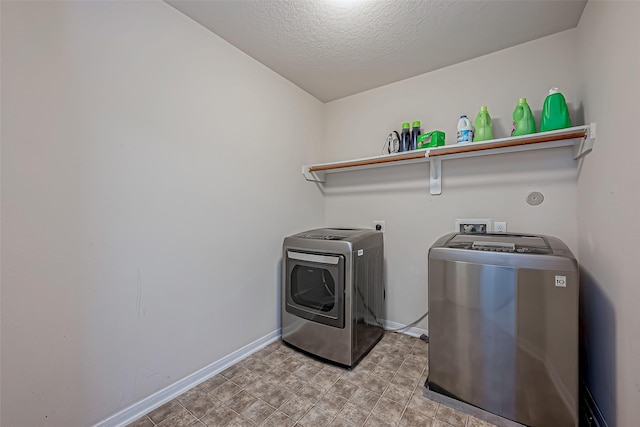 washroom with laundry area, baseboards, washer and clothes dryer, and a textured ceiling