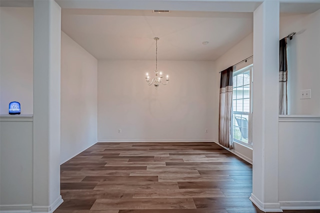 unfurnished dining area with baseboards, visible vents, an inviting chandelier, and wood finished floors