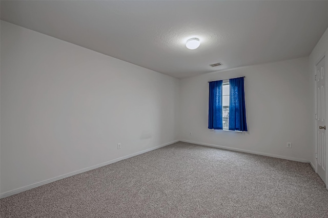 spare room featuring carpet floors, baseboards, visible vents, and a textured ceiling