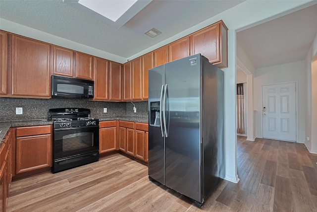 9514 Barr Spring Dr, Humble, TX 77396 - kitchen with black appliances, light wood-style flooring, brown cabinets, and decorative backsplash