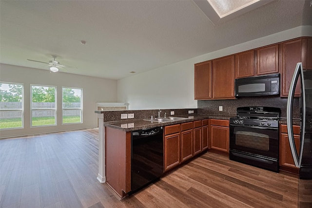 9514 Barr Spring Dr, Humble, TX 77396 - kitchen with black appliances, a peninsula, wood finished floors, and decorative backsplash