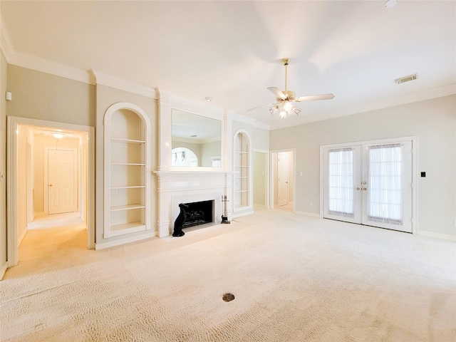 unfurnished living room featuring french doors, visible vents, a large fireplace, ornamental molding, and carpet