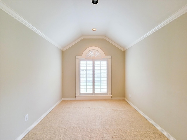 empty room with baseboards, ornamental molding, light carpet, and vaulted ceiling