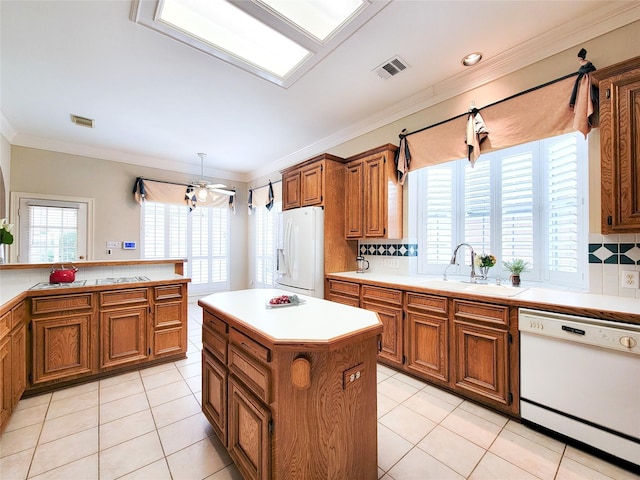 kitchen featuring a sink, white appliances, light countertops, brown cabinetry, and visible vents