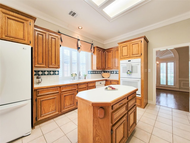 kitchen with white appliances, light countertops, light tile patterned floors, a kitchen island, and visible vents
