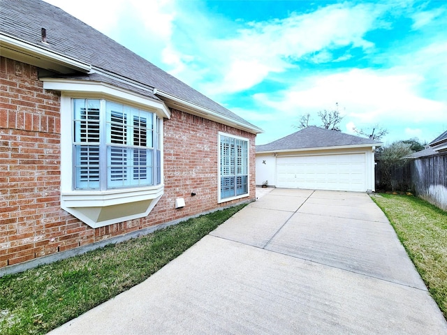 view of side of property featuring brick siding, a garage, roof with shingles, and fence