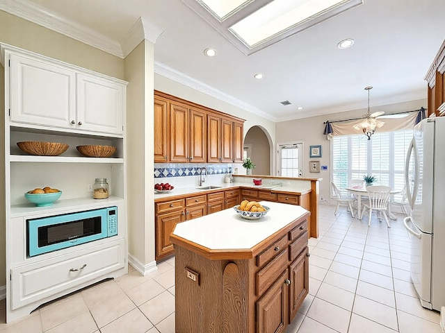 kitchen with arched walkways, built in microwave, a sink, light countertops, and freestanding refrigerator