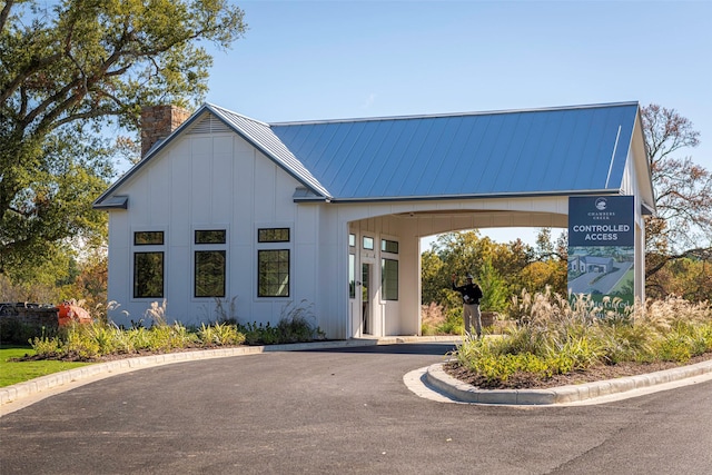 view of front of house featuring board and batten siding, a standing seam roof, metal roof, and a chimney