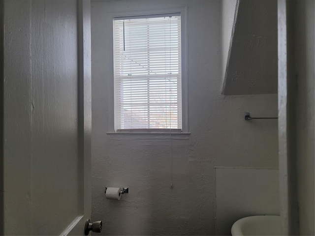 bathroom featuring a textured wall and toilet