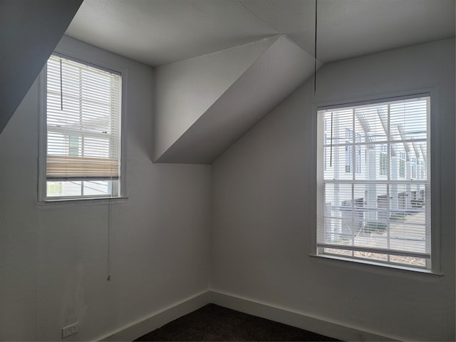 bonus room with lofted ceiling and baseboards