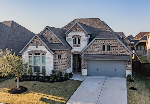 french country style house with stone siding, brick siding, concrete driveway, and a front lawn