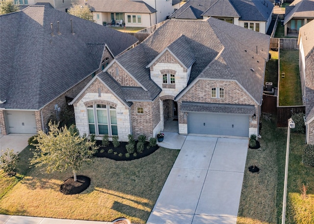 view of front of home featuring a garage, a shingled roof, brick siding, stone siding, and concrete driveway