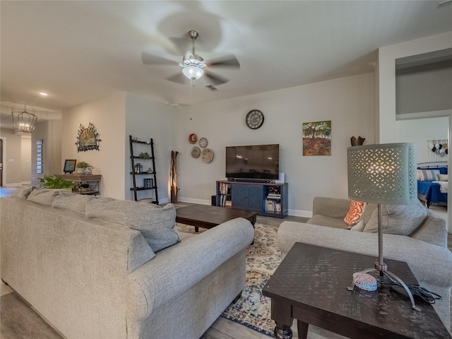 living room with visible vents, baseboards, wood finished floors, and ceiling fan with notable chandelier