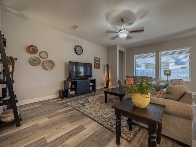 living room with baseboards, visible vents, ceiling fan, and wood finished floors