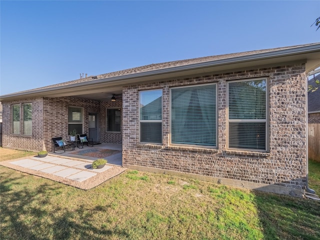 rear view of property with a patio area, a yard, and brick siding